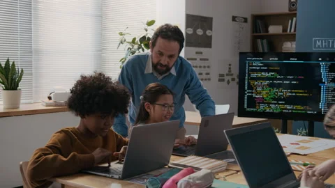 Male Coding Teacher Checking on Kids Working on Laptops at Lesson 動画素材 306933358