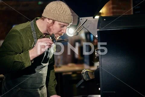 Male Coffee Shop Owner At Coffee Machine Smelling Coffee