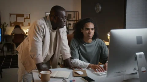 Male Colleagues Collaborating on Computer Working Late in Office Stock Footage 348155779