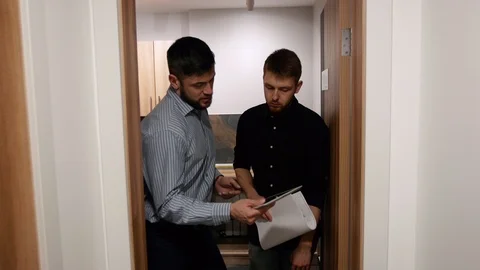 Male colleagues discuss work issues going in the corridor of the office building Stock Footage 103940983