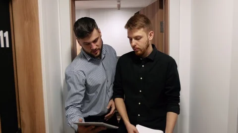 Male colleagues discuss work issues going in the corridor of the office building Stock Footage 104669780