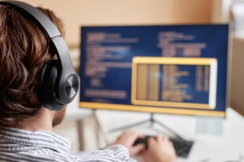 Male Computer Programmer Coding in Office and Wearing Big Headphones Stockfoto's