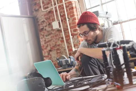 Male computer programmer working at laptop in workshop Stock Photos
