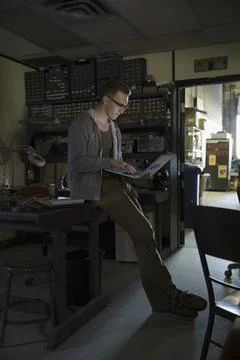 Male computer programmer working at laptop in dark workshop Stock-Fotos