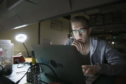 Male computer programmer working at laptop in dark workshop Stock-Fotos