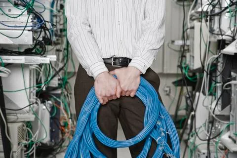 Male computer technician holding CAT 5 cables and standing in the aisle of a Stock Photos
