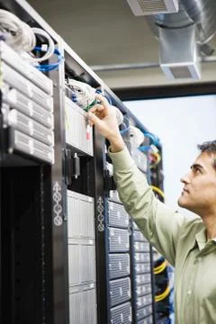 Male computer technician working on servers in a computer server farm. Stock Photos