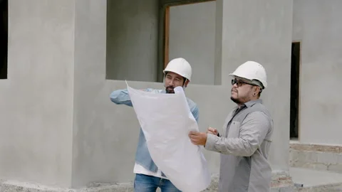 Male construction engineer, standing talking with builder while holding Stock Footage 253078915