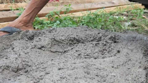 A male construction worker is mixing sand and cement using a hoe Stock Footage 307003486