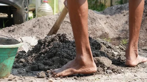 A male construction worker is mixing sand and cement using a hoe Stock Footage 307038601