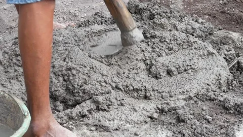 A male construction worker is mixing sand and cement using a hoe Stock Footage 307038623