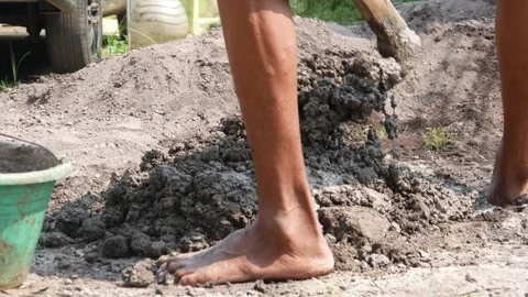 A male construction worker is mixing sand and cement using a hoe Stock Footage 307038752