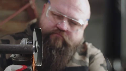 Male construction worker in protective glasses works by cutting metal pipe with Stock Footage 172405083