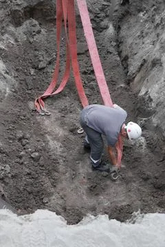 Male construction worker securing hooks in excavation site Stock Photos