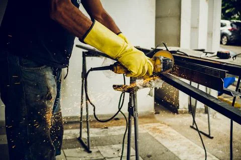 Male construction worker using a tool to cut and polish metal Stock Photos