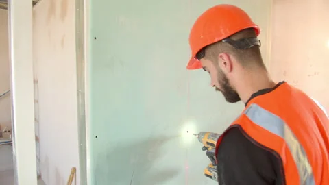 Male contractor in hardhat installing drywall during renovation Stock Footage 154451518