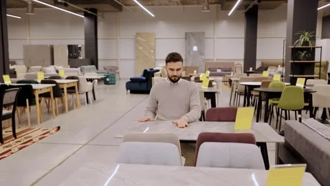 Male customer considering new dining furniture in modern showroom, shopping Stock Footage 334654093