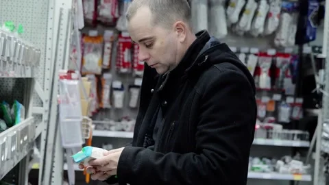 Male customer examining electrical component in hardware store, focusing Stock Footage 338217761