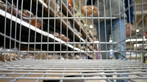A male customer putting a pack of sliced wheat bread in a shopping cart Stock Footage 317685246