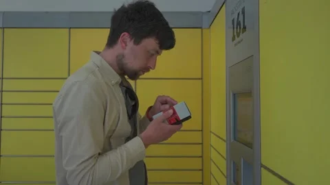 Male customer using self-service automated delivery terminal to send package or Stock Footage 242792059
