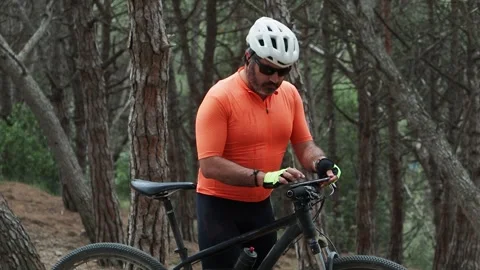 Male cyclist looking at the cycle computer of mountain bike in a forest. Stock Footage 243568130