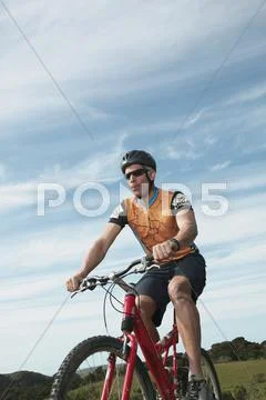 Male cyclist riding under blue sky Stock Photos