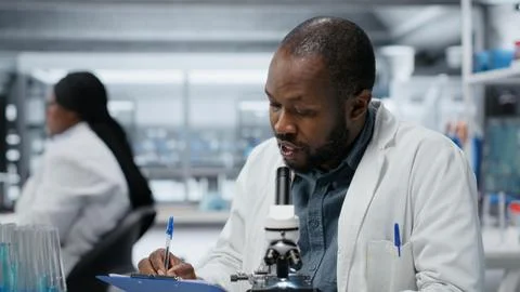 Male cytotechnologist using optical microscope to study microorganisms Stock Photos