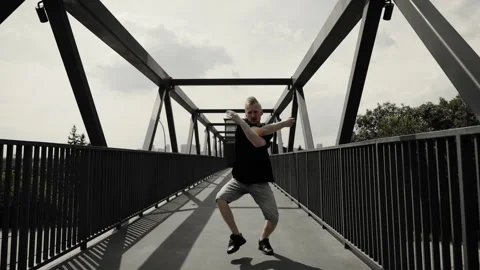 A male dancer is actively dancing on camera in the middle of a pedestrian Stock Footage 252069815