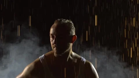 Male dancer dancing elements of salsa in the pouring rain in a dark smoky studio Stock Footage 143818151