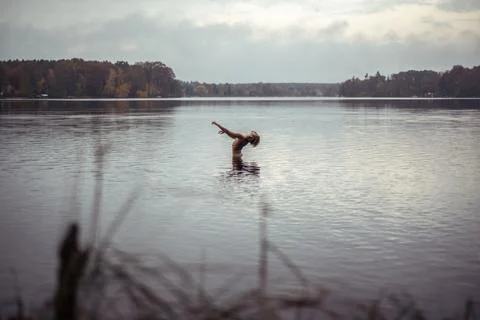 Male dancer in natural back arch towards sky in middle of pretty lake Stock Photos