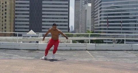 Male dancer performing flips on top of a parking garage Stock Footage 97390140