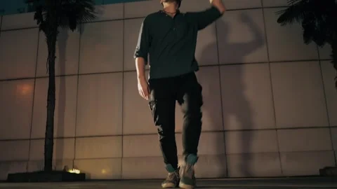 Male dancer twisting gracefully under city lights at night, expressive movements Video stock 303645964