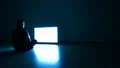 The male in the dark room sitting on the floor near the television 4k or 4k+ Resolution
