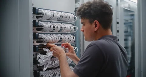 Male Data Center Engineer Connecting RJ45 Ethernet Cables to Network Switch Stockbeeldmateriaal 344956821