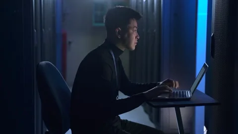 Male data engineer checking equipment and working with laptop at table in server Stock Footage 166837425