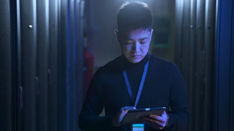 Male data engineer or scientist using tablet and examining hardware, walking in Stock Footage 166837364