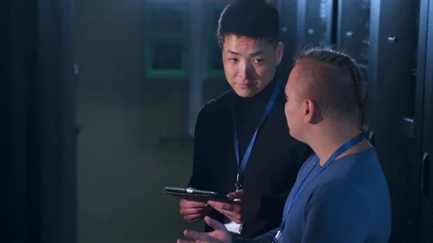 Male data engineers talking and working together while standing in render farm Stock Footage 163784649