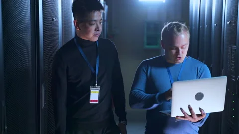Male data engineers talking and working with computer while walking in server Stock Footage 163816232