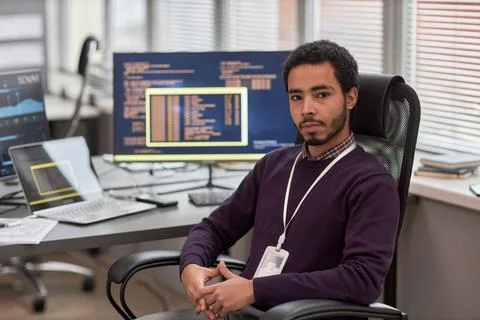 Male data scientist looking at camera while sitting at desk in office Foto stock