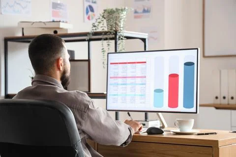 Male data scientist working with computer at desk in office, back view 写真素材