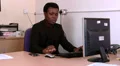Male at desk answers his mobile phone HD Footage