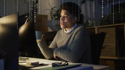 Male developer reaching keyboard while checking screen, sipping mug while binary Stock Footage 333351530