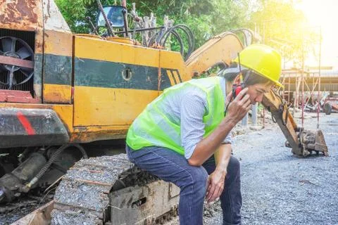 Male developer sitting and talking on the walkie talkie with an excavator Stock Photos