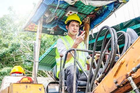 Male developer sitting operator driving excavator and talking the walkie talkie Stock Photos