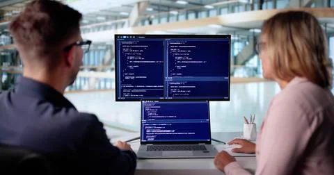 Male Developer Typing Code On Laptop With Female Trainee In Office. Stockfoto's