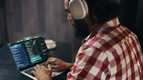 Male developer wearing headset coding on laptop with holographic display 스톡 동영상 329507044