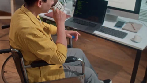 Male Developer in Wheelchair Drinking Coffee when Coding at Office Stock Footage 265073662