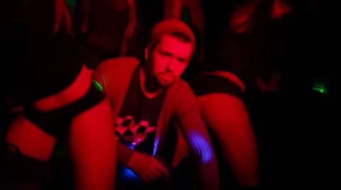 Male DJ sitting between two girls shaking fanny on stage at club. Stock Footage 63659345