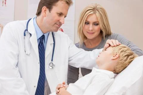Male doctor examining boy child with mother Stock Photos