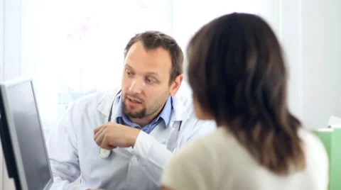 Male doctor explaining something on computer monitor to female patient HD Video stock 7755687